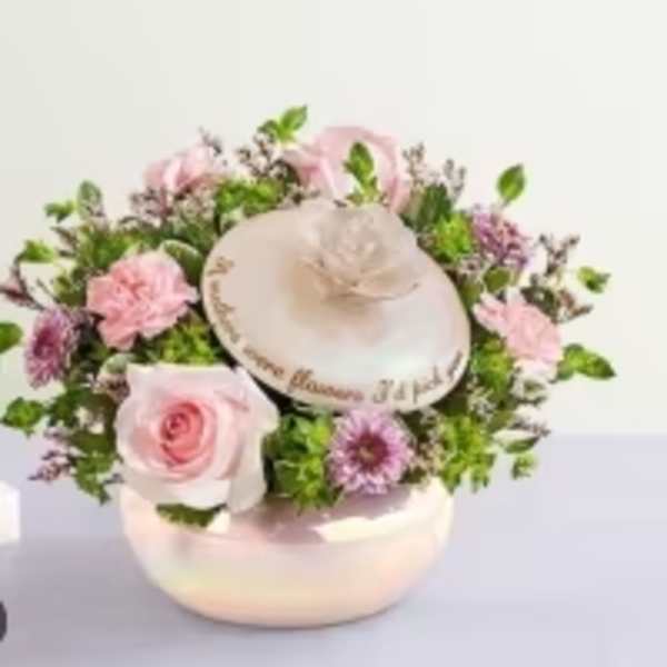 Pink roses and purple flowers arranged around a decorative hat box
