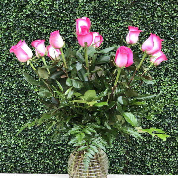Pink roses in a clear glass vase with greenery