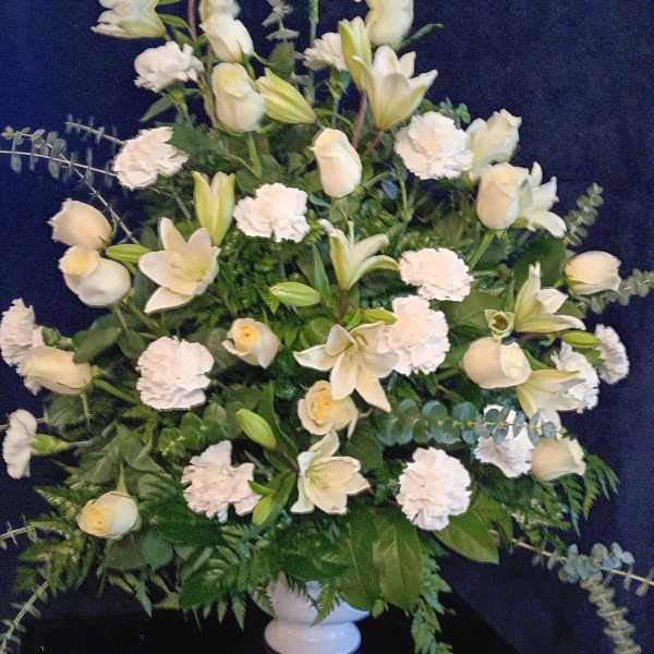 White floral arrangement with lilies, roses, and carnations in a vase