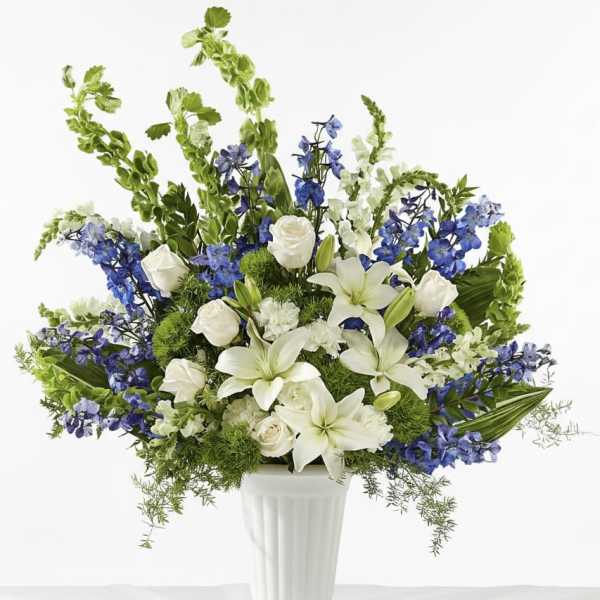 White lilies and roses with blue flowers in a white vase