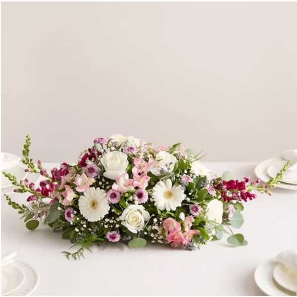 Low floral centerpiece with white and pink flowers on a table