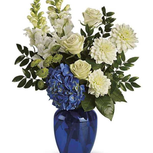 White and blue floral arrangement in a cobalt blue vase