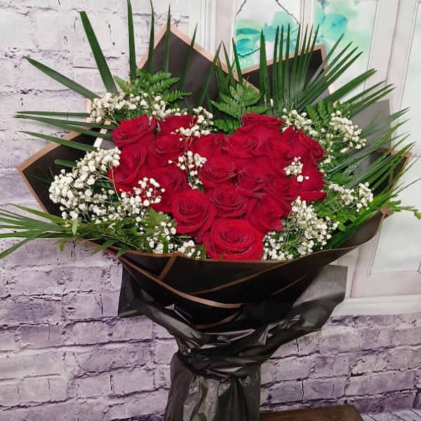 Bouquet of red roses with white baby's breath in black wrap