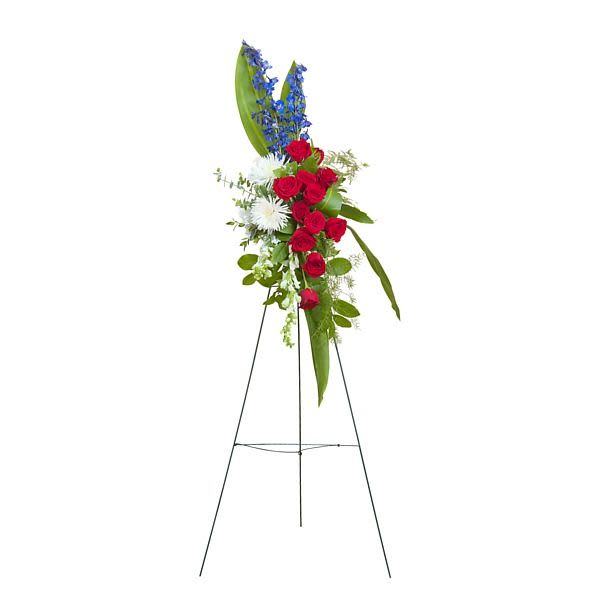 Standing red, white, and blue floral spray with roses, mums, and delphinium on a metal easel.
