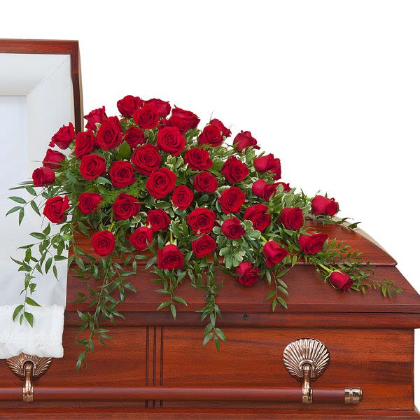 Red rose casket spray arranged on a polished wood coffin