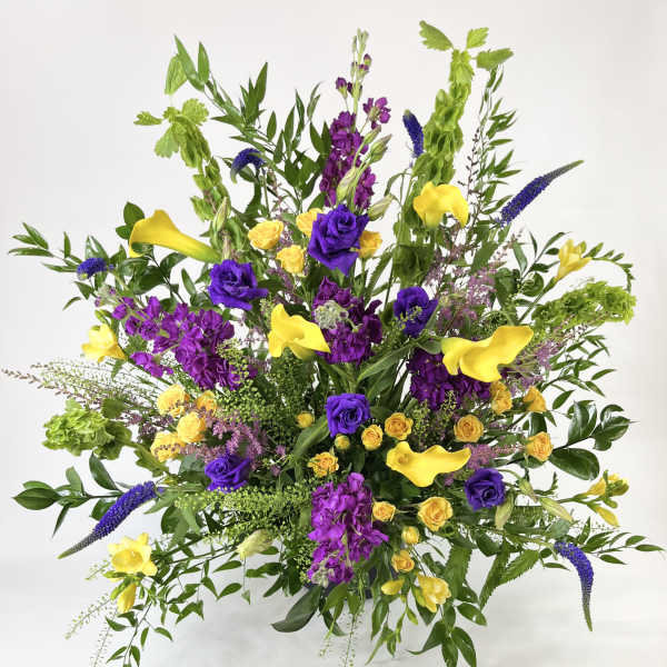 Large bouquet with yellow calla lilies, purple roses, and mixed greenery