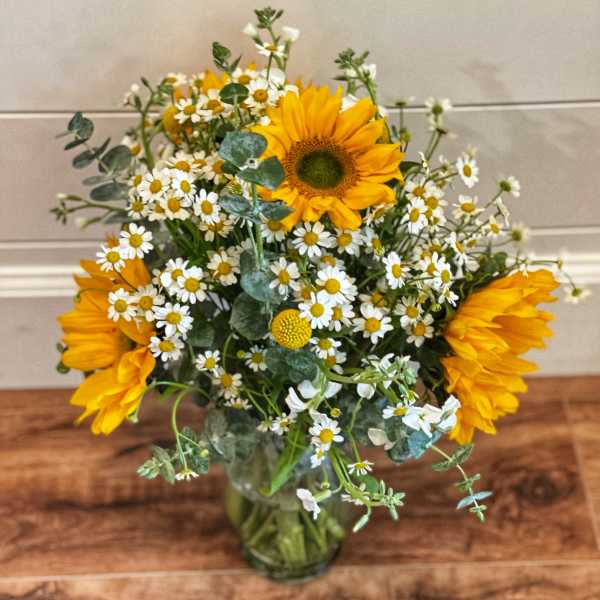 Sunflowers and white daisies arranged in a glass vase