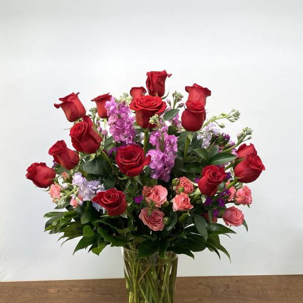 Red roses and pink flowers arranged in a clear glass vase