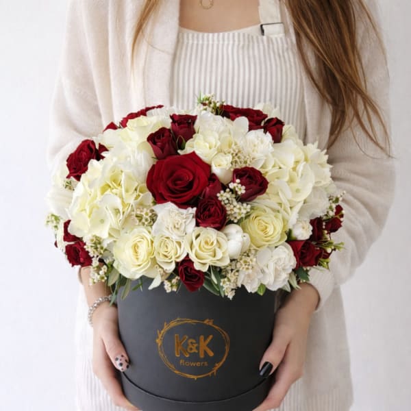 Red and white roses arranged in a black round box