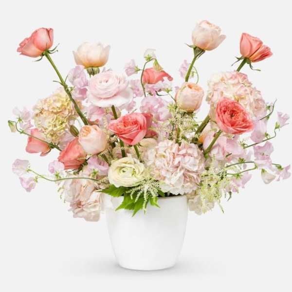 Pastel bouquet of roses and ranunculus in a white vase