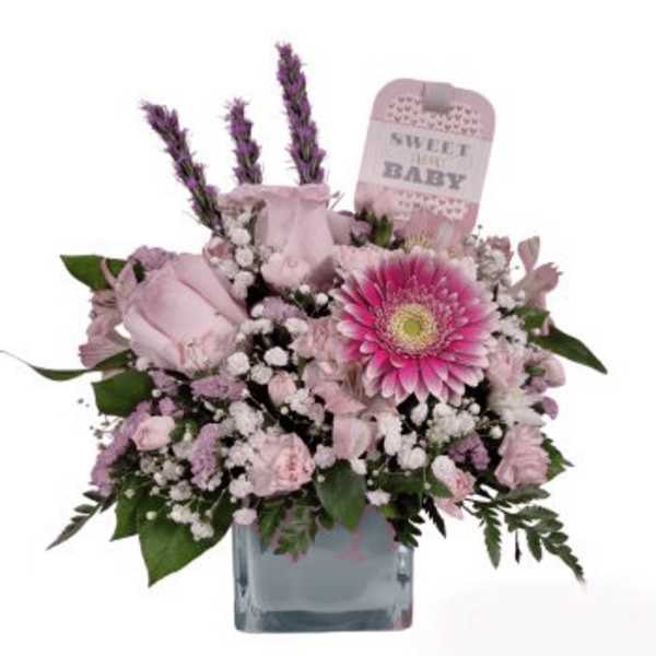 Pink floral arrangement in a glass vase with a baby card