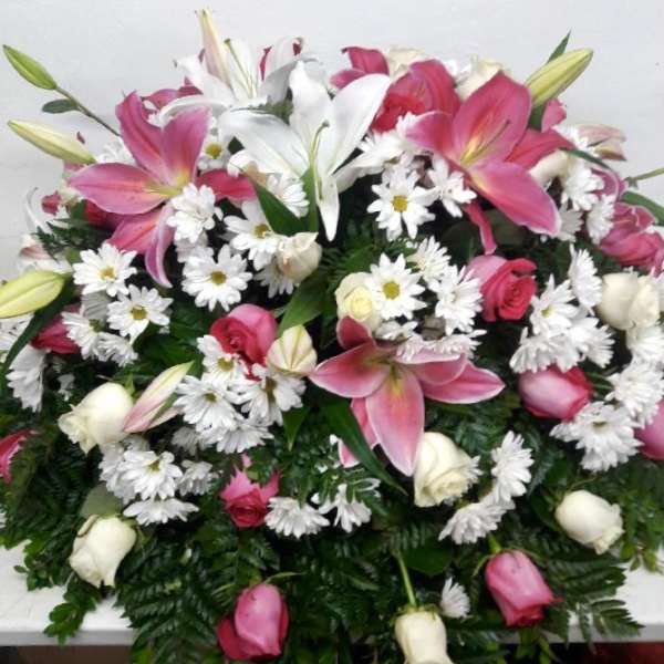 Pink lilies, white daisies, and roses arranged in a dense bouquet