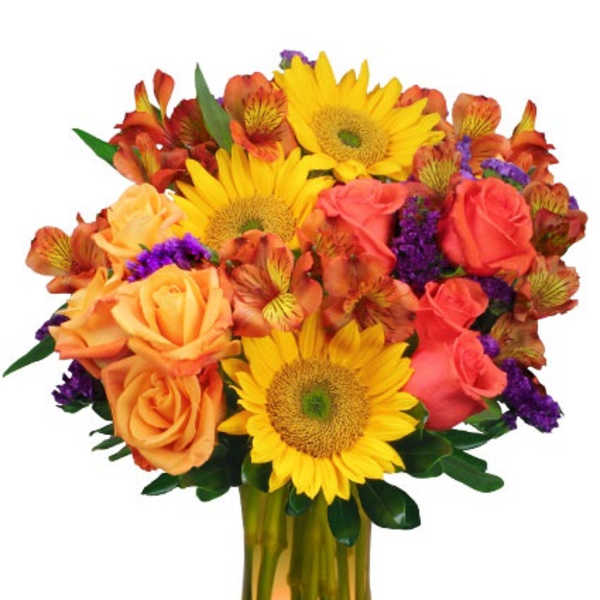 Bright arrangement of yellow sunflowers, orange roses, and purple accents in an amber glass vase
