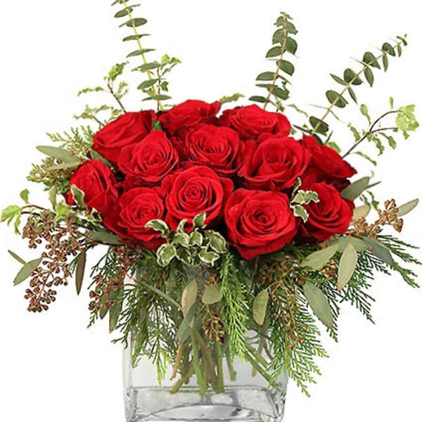 Low arrangement of red roses with assorted foliage in a square clear glass vase