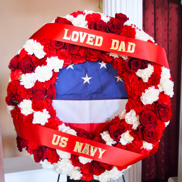 Red and white floral wreath with a ribbon reading "LOVED DAD" and "US NAVY"
