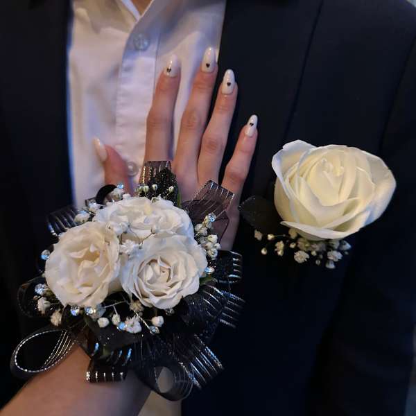 White rose corsage and boutonniere on a black suit jacket