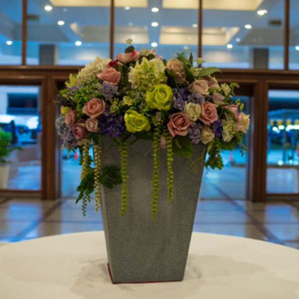 Mixed pink and green floral arrangement in a tall gray vase