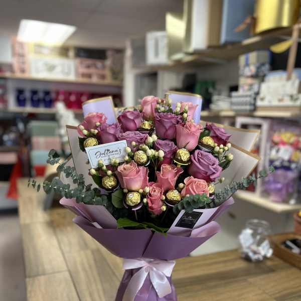 Bouquet of pink and purple roses with gold chocolates in lavender wrap