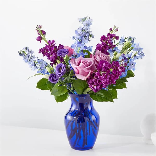 Pink and purple flowers arranged in a blue glass vase
