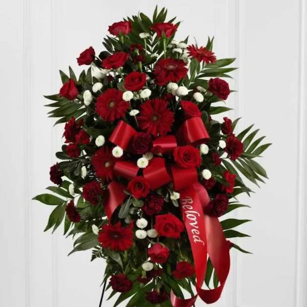Standing spray of red roses and red daisies with a red ribbon