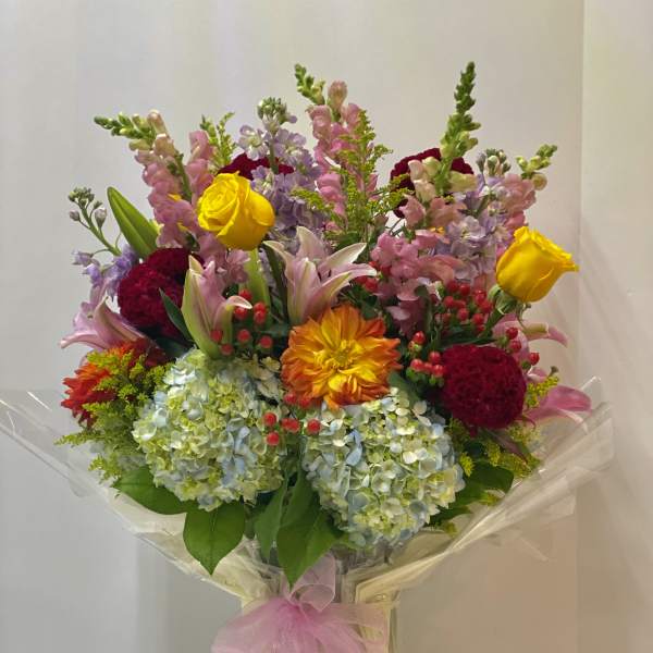 Colorful mixed bouquet in a clear vase with a pink ribbon