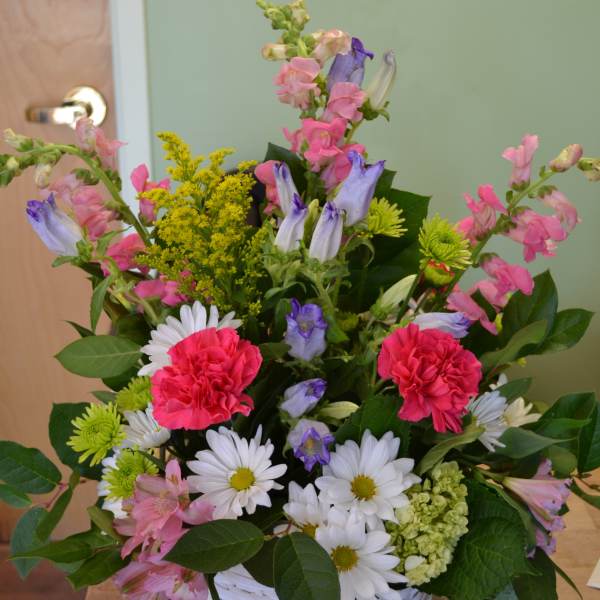 Mixed bouquet in a white basket with pink, purple, and white flowers
