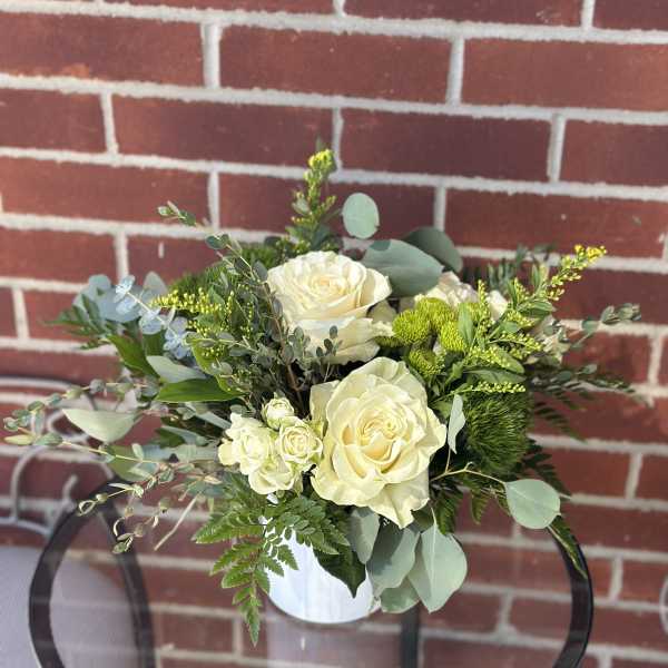 White rose bouquet in a white vase with mixed greenery