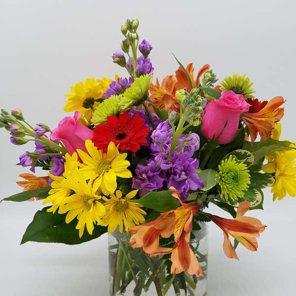 Mixed bouquet of colorful flowers in a clear glass vase