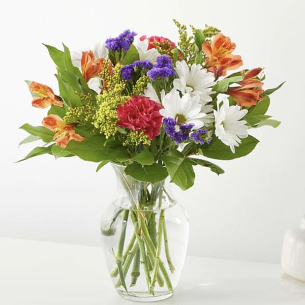 Mixed bouquet of daisies, carnations, and alstroemeria in a clear glass vase