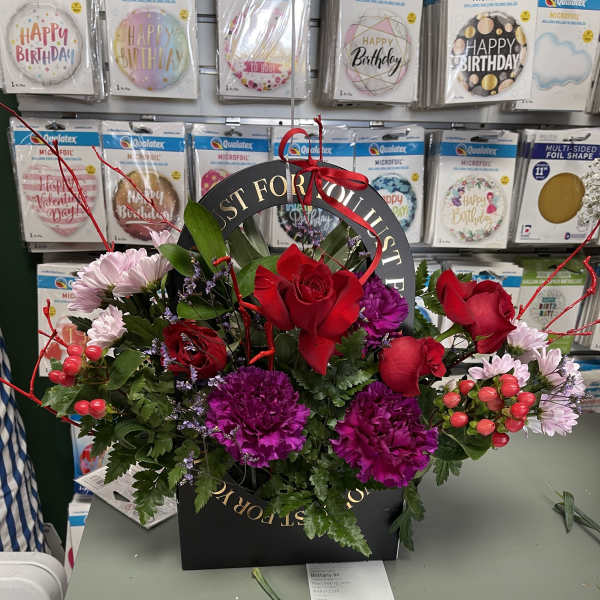 Birthday flower arrangement in a black gift box with red roses and purple blooms