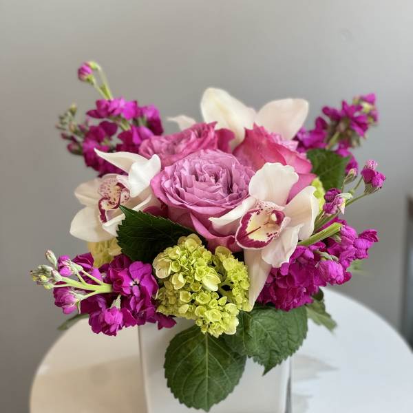 Pink and white floral arrangement in a square glass vase