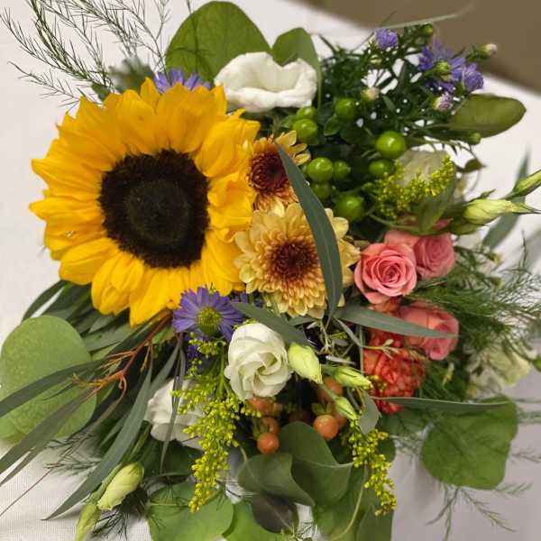 Mixed bouquet with a large sunflower, pink roses, and white blooms
