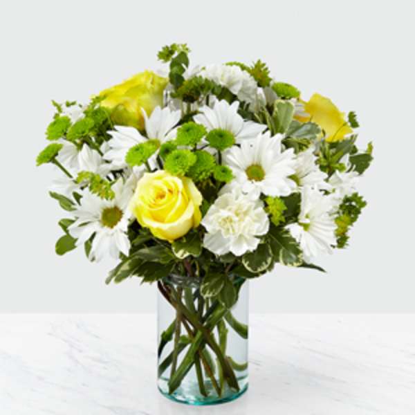 Yellow roses and white daisies in a clear glass vase