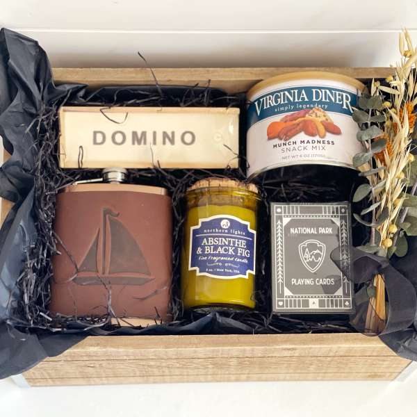 Gift box with snacks, candle, playing cards, and dried flowers