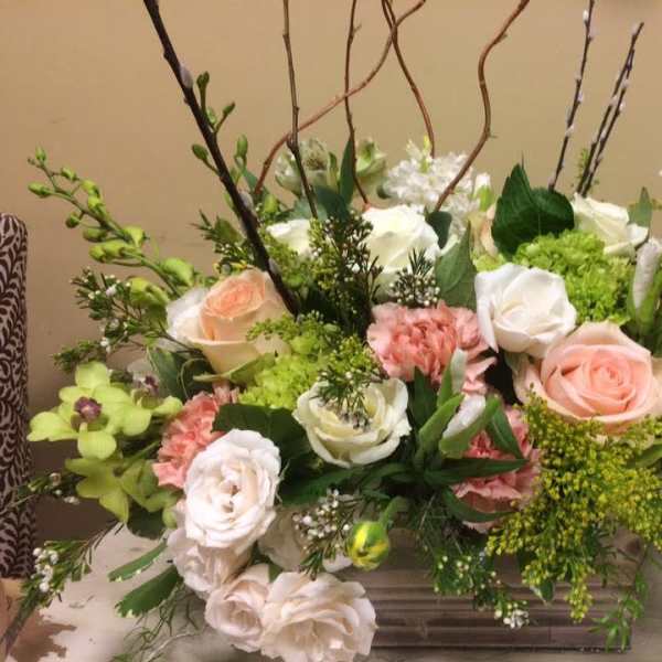 Mixed bouquet of roses, carnations, and green blooms in a low rectangular container