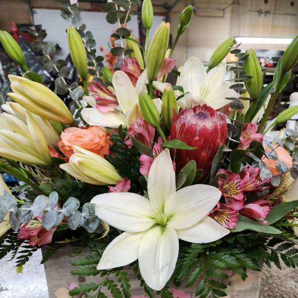 Mixed bouquet with white lilies, pink flowers, and eucalyptus in a wooden box