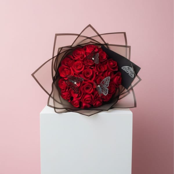 Bouquet of red roses wrapped in black paper with butterfly accents