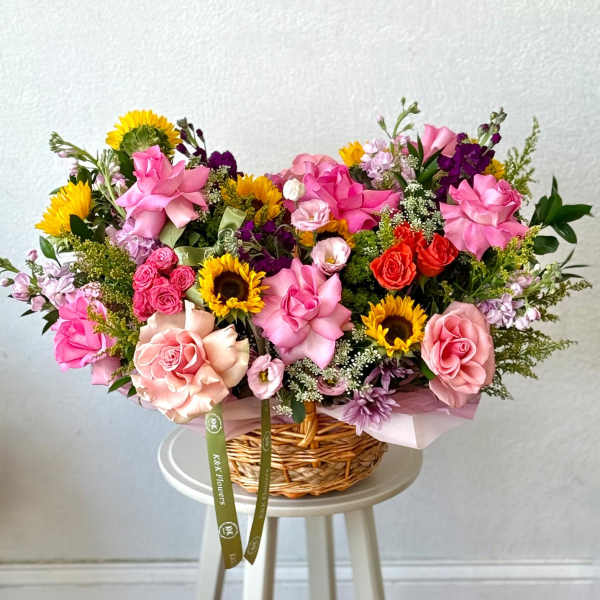 Mixed bouquet in a wicker basket with pink roses and sunflowers