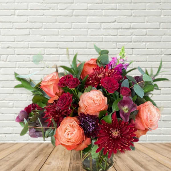 Bouquet of peach and burgundy flowers in a glass vase