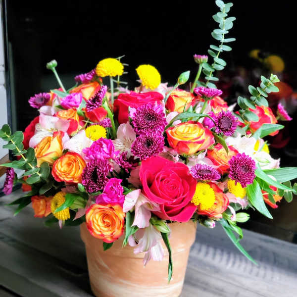 Mixed bouquet of roses, chrysanthemums, and alstroemeria in a peach vase