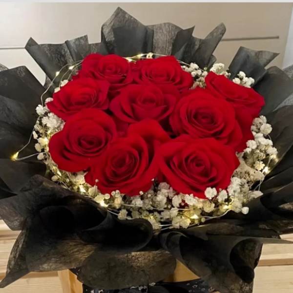 Bouquet of red roses with white baby's breath wrapped in black paper