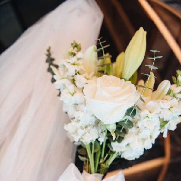 White bridal bouquet with roses, lilies, and a satin bow