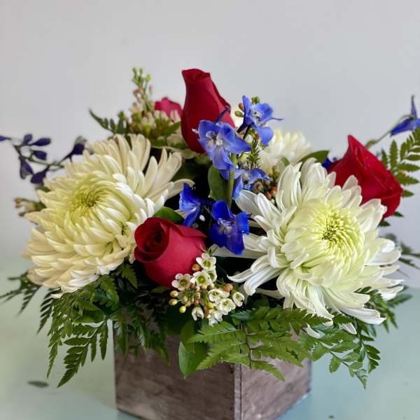 Red roses and white chrysanthemums in a wooden box with blue flowers