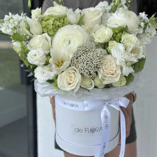 White rose and ranunculus bouquet in a round hat box with ribbon