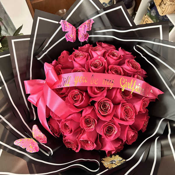 Bouquet of hot pink roses wrapped in black paper with a pink ribbon