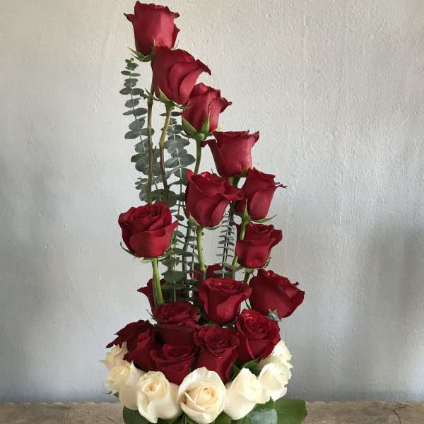Tall arrangement of red and white roses in a white cylinder vase