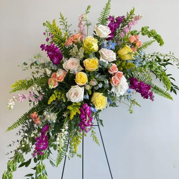 Large standing floral spray with multicolored roses and cascading greenery