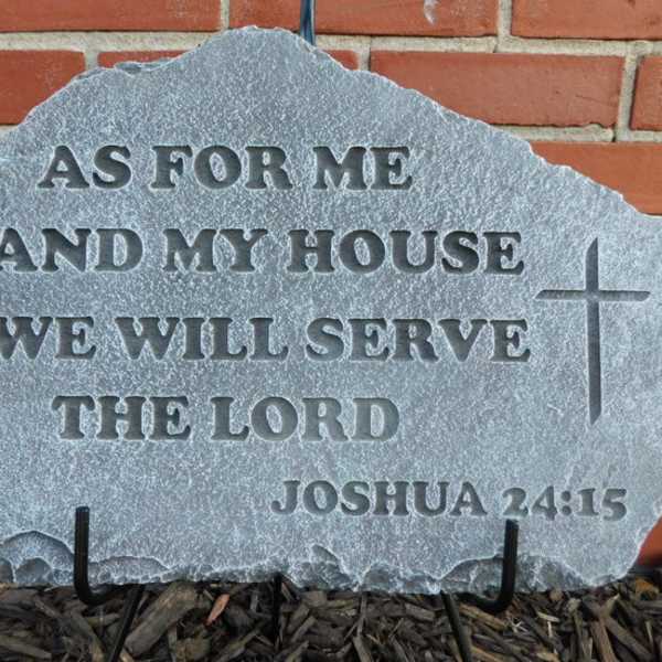 Engraved stone plaque with a Bible verse and cross against a brick wall