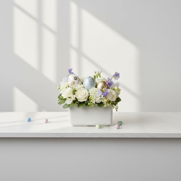 White floral arrangement with pastel Easter eggs in a rectangular vase