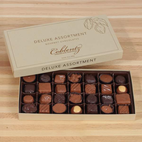 Open box of assorted chocolates on a wooden surface
